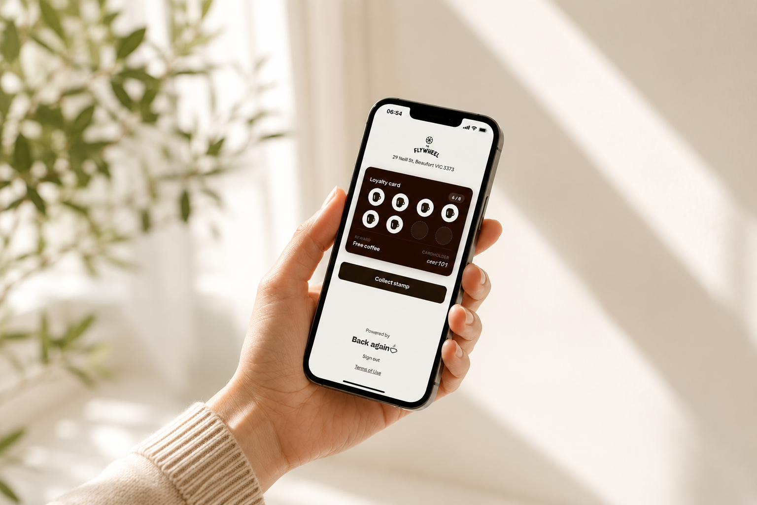 Customer holding phone with Back Again digital loyalty card on screen